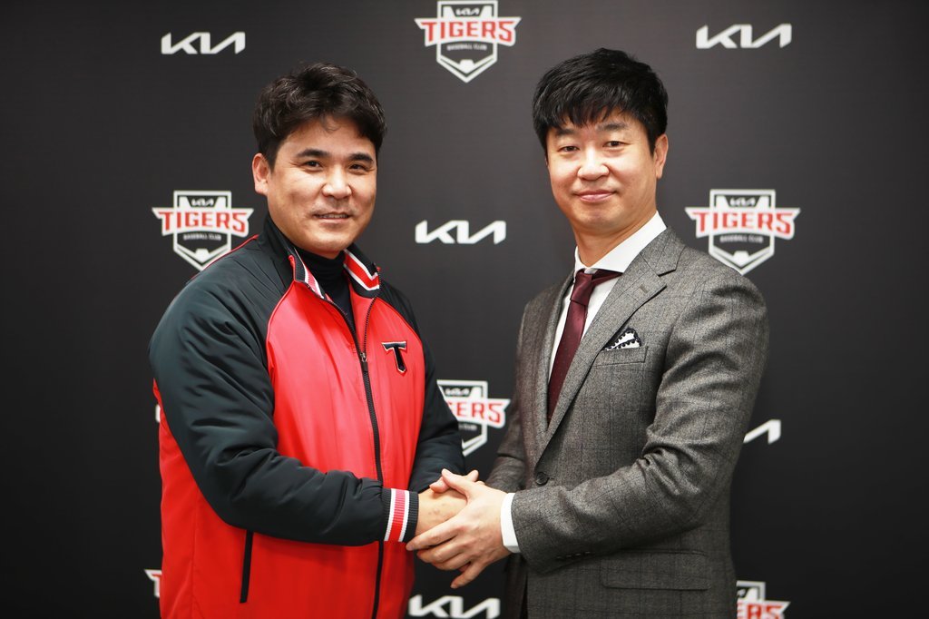 Kim Jong-kook (R), tapped as the new manager of the Kia Tigers, shakes hands with Jang Jung-suk, general manager of the club, after signing a contract on Sunday, in this photo provided by the team. (Kia Tigers)