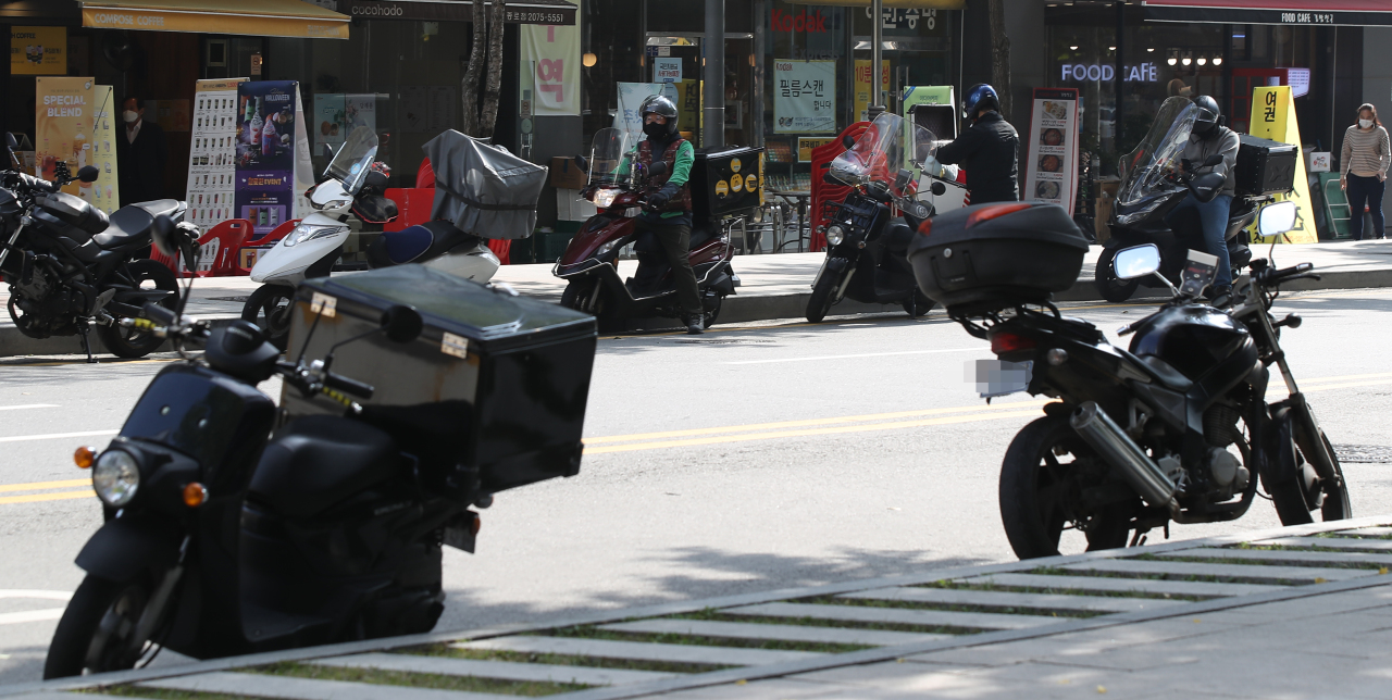 Delivery riders are seen on streets in Seoul. (Yonhap)
