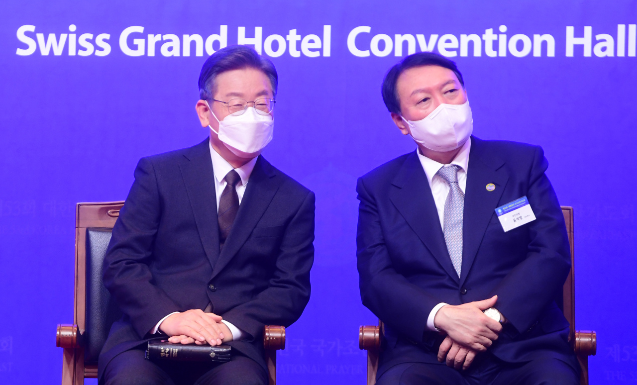 Lee Jae-myung (L), the presidential nominee of the ruling Democratic Party, and Yoon Suk-yeol, the nominee of the main opposition People Power Party, attend the Korea National Prayer Breakfast at a Seoul hotel last Thursday. (Yonhap)
