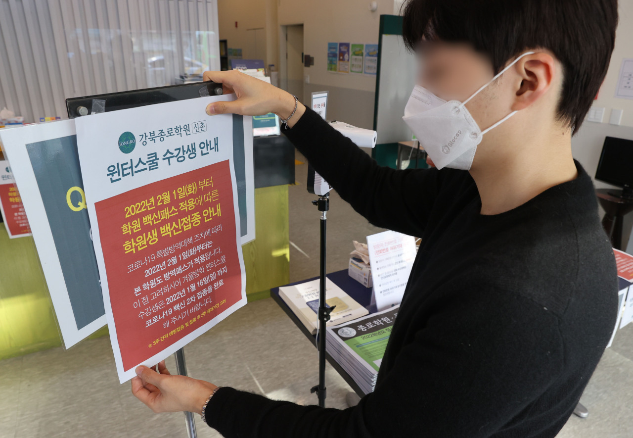 An employee posts a notice informing visitors of a new requirement for vaccine passes at a cram school in Seoul on Tuesday. (Yonhap)