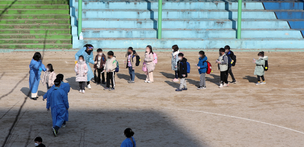 Kids on Tuesday line up to get a COVID-19 test after an outbreak at the school in Gwangju. (Yonhap)