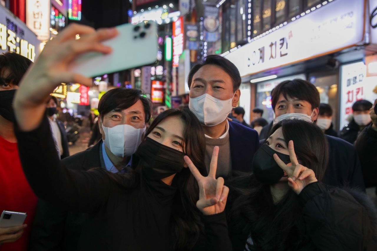 Yoon Suk-yeol, presidential nominee of the main opposition People Power Party (center), poses with university students after a meeting with student party members, near Sillim Station in Seoul on Nov. 26. (PPP)