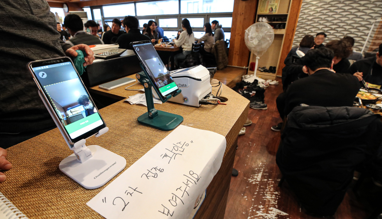 Mobile phones are installed at a restaurant in Seoul to check visitors' COVID-19 vaccine pass through a quick-response code service, on Monday. (Yonhap)