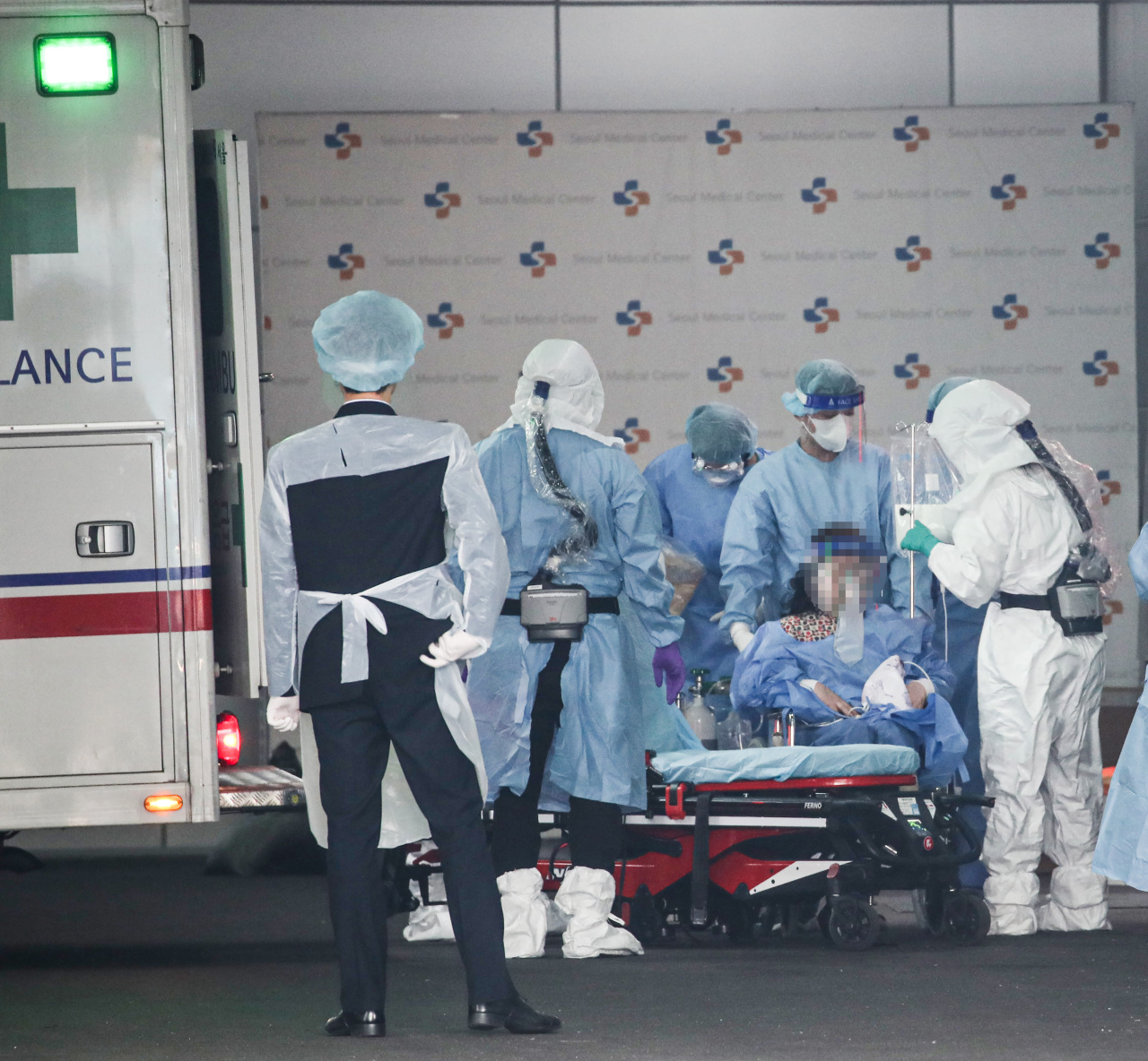 A COVID-19 patient is being transported on a stretcher from an ambulance at Seoul Medical Center in Seoul on Wednesday. (Yonhap)