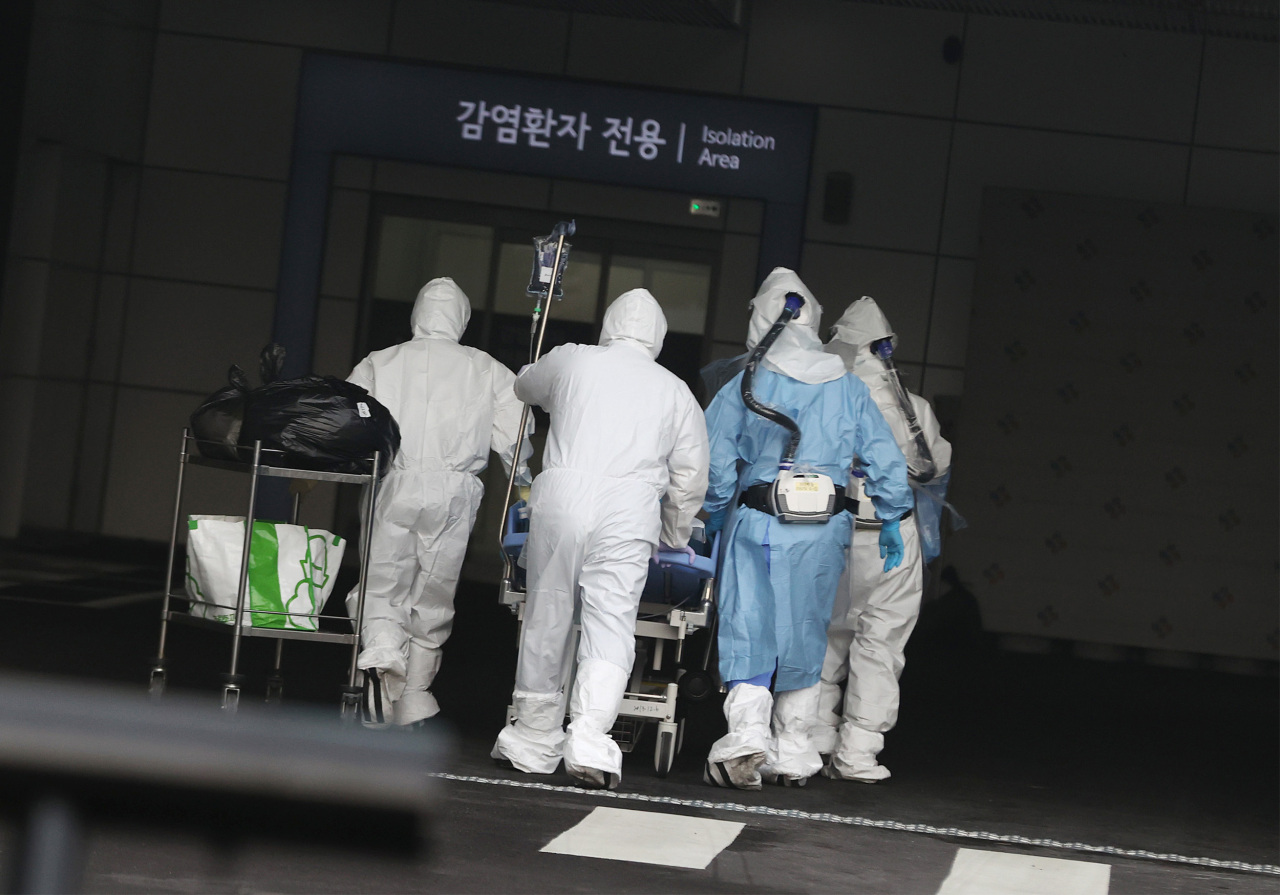 Health care workers transfer a patient with COVID-19 at a local hospital in Seoul, Thursday. (Yonhap)
