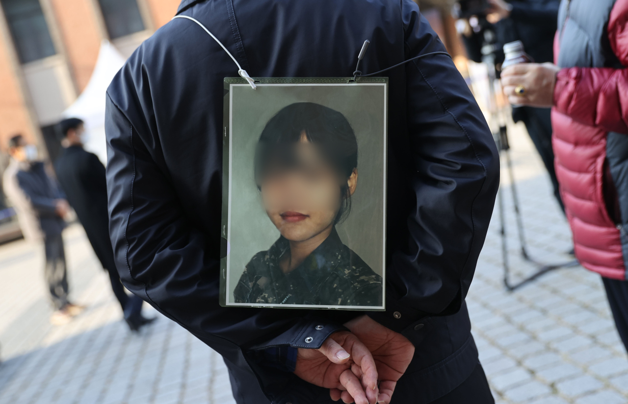 This photo, taken Nov. 25, 2021, shows the father of a deceased Air Force noncommissioned officer holding a picture of his daughter during a protest in Seoul. She took her own life in May after being sexually harassed by a colleague. (Yonhap)