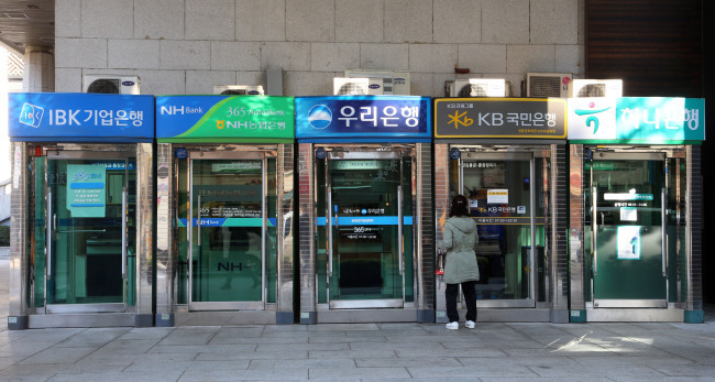 A citizen passes by a row of ATM machines in Seoul. (Yonhap)