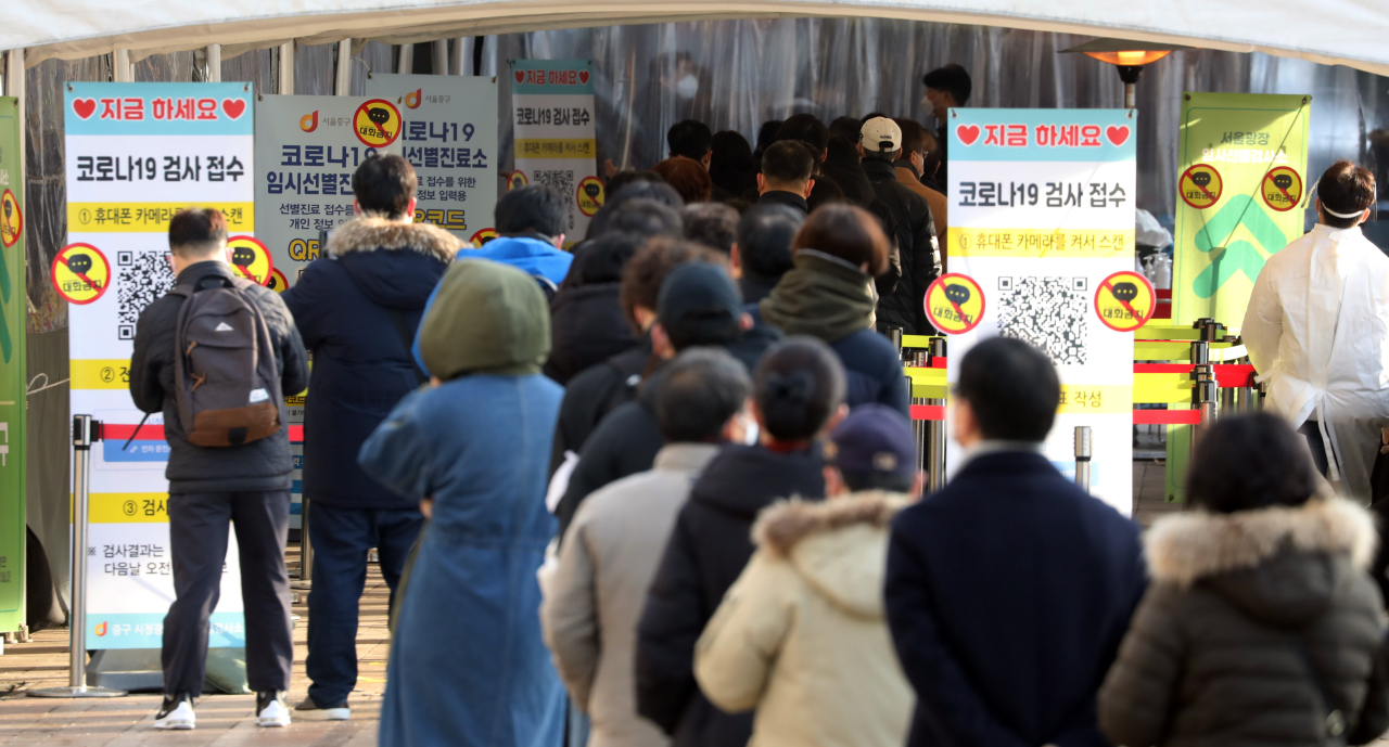 People wait in a long line to take coronavirus tests at a testing station in Seoul Plaza in central Seoul on Monday. (Yonhap)