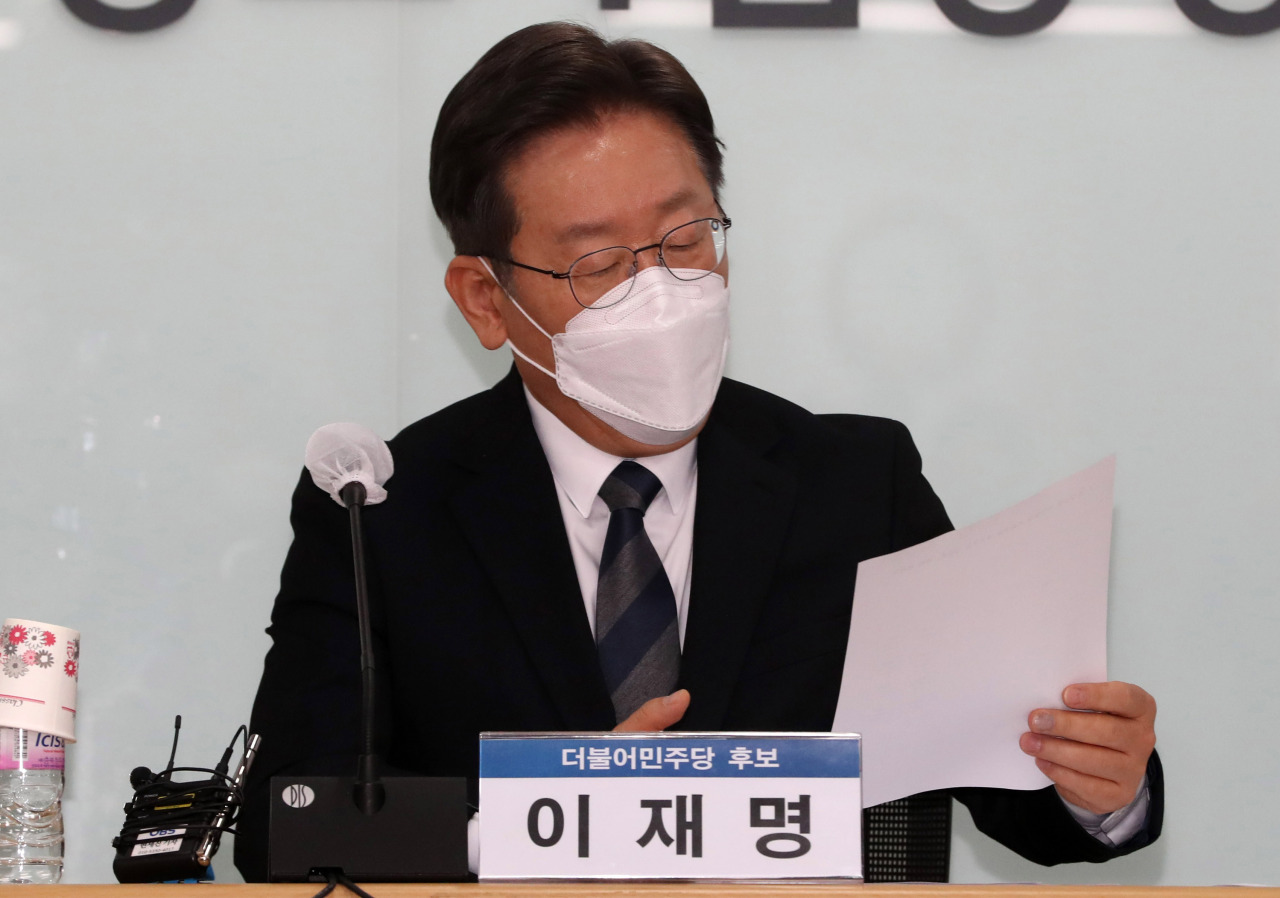 Lee Jae-myung, the presidential candidate of the ruling Democratic Party, looks at a report during his meeting with small business owners and self-employed people at the Korea Federation of SMEs in Seoul on Monday. (Yonhap)