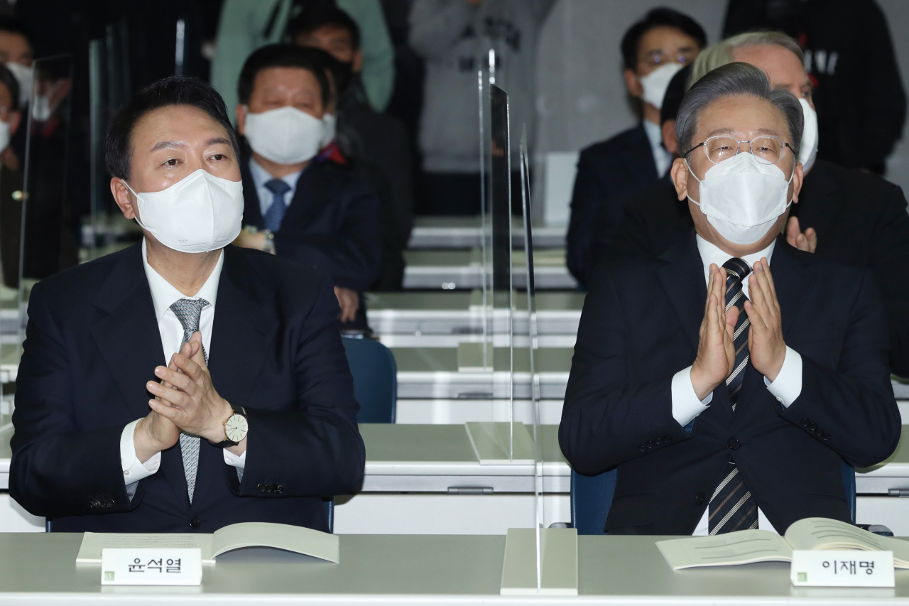 This photo taken on Dec. 9, 2021, shows Yoon Suk-yeol, the presidential candidate of the main opposition People Power Party, and Lee Jae-myung, the presidential nominee of the ruling Democratic Party, attending at an event commemorating late president Kim Dae-jung in Seoul.(Yonhap)