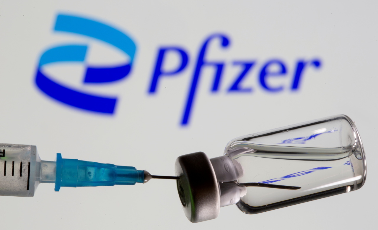 Syringe and vial are seen in front of displayed Pfizer logo (Reuters-Yonhap)
