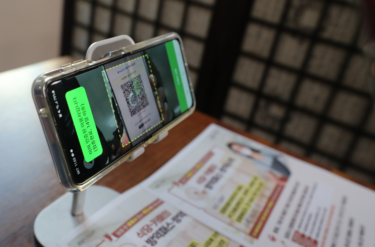 Mobile phones are installed at a restaurant in Seoul to check visitors' COVID-19 vaccine pass through a quick-response code service, on Dec. 13. (Yonhap)