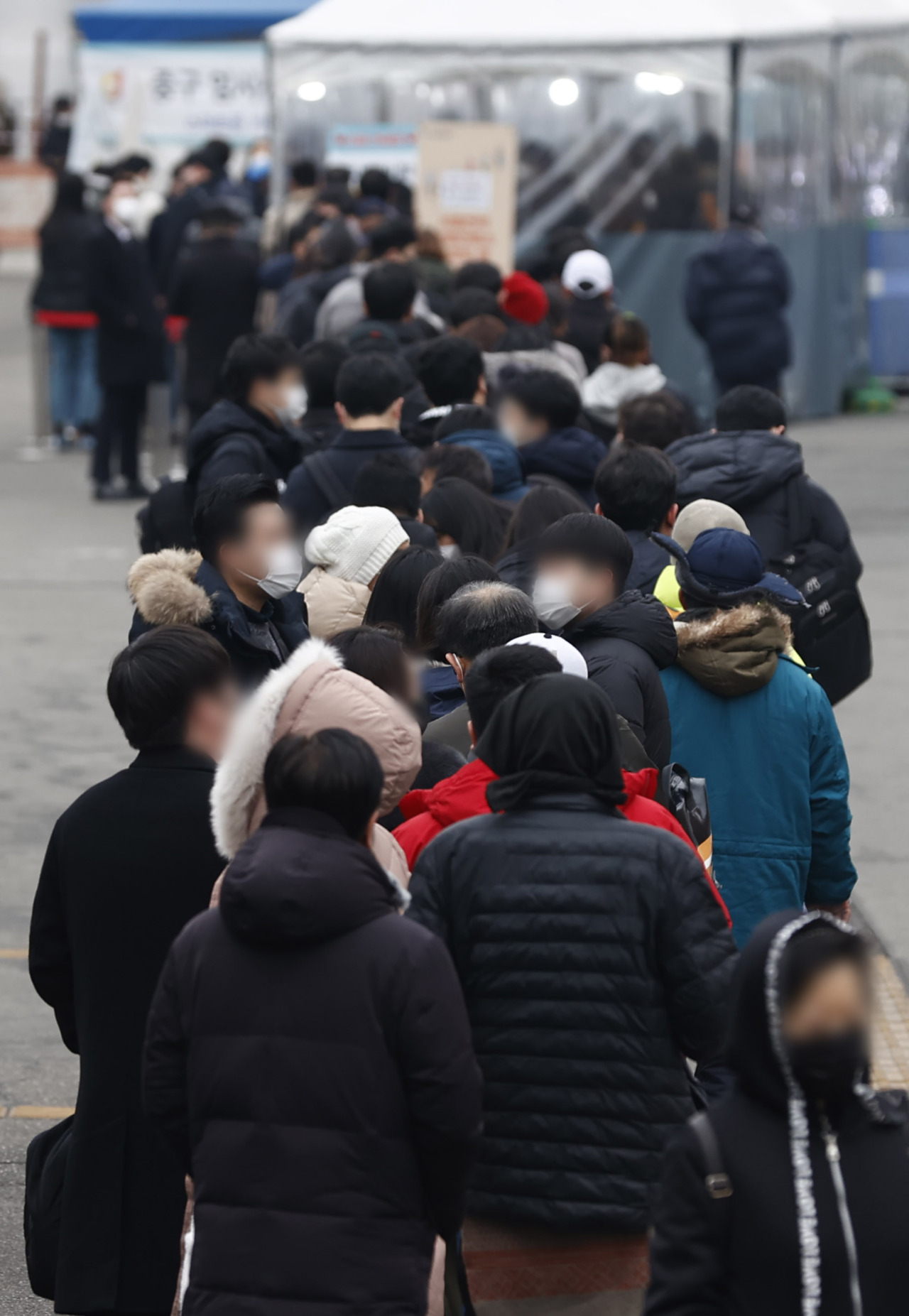 People stand in line to take coronavirus tests at a screening clinic in front of Seoul Station on Friday. (Yonhap)
