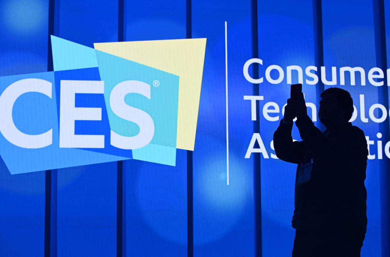 In this file photo taken on Jan. 6, 2020, an attendee photographs a sign next to the CES logo ahead of the first keynote address at the 2020 Consumer Electronics Show in Las Vegas, Nevada. - Multiple major companies have announced they will cancel or limit their attendance to the 2022 Consumer Electronics Show -- the tech industry's annual mass-gathering in Las Vegas -- due to Covid-19 variant Omicron's rapid spread. The popular four-day conference, which had planned for a grand return in 2022 with in-person attendance, is still scheduled to start on Jan. 5, with the press getting early access two days beforehand. (AFP-Yonhap)