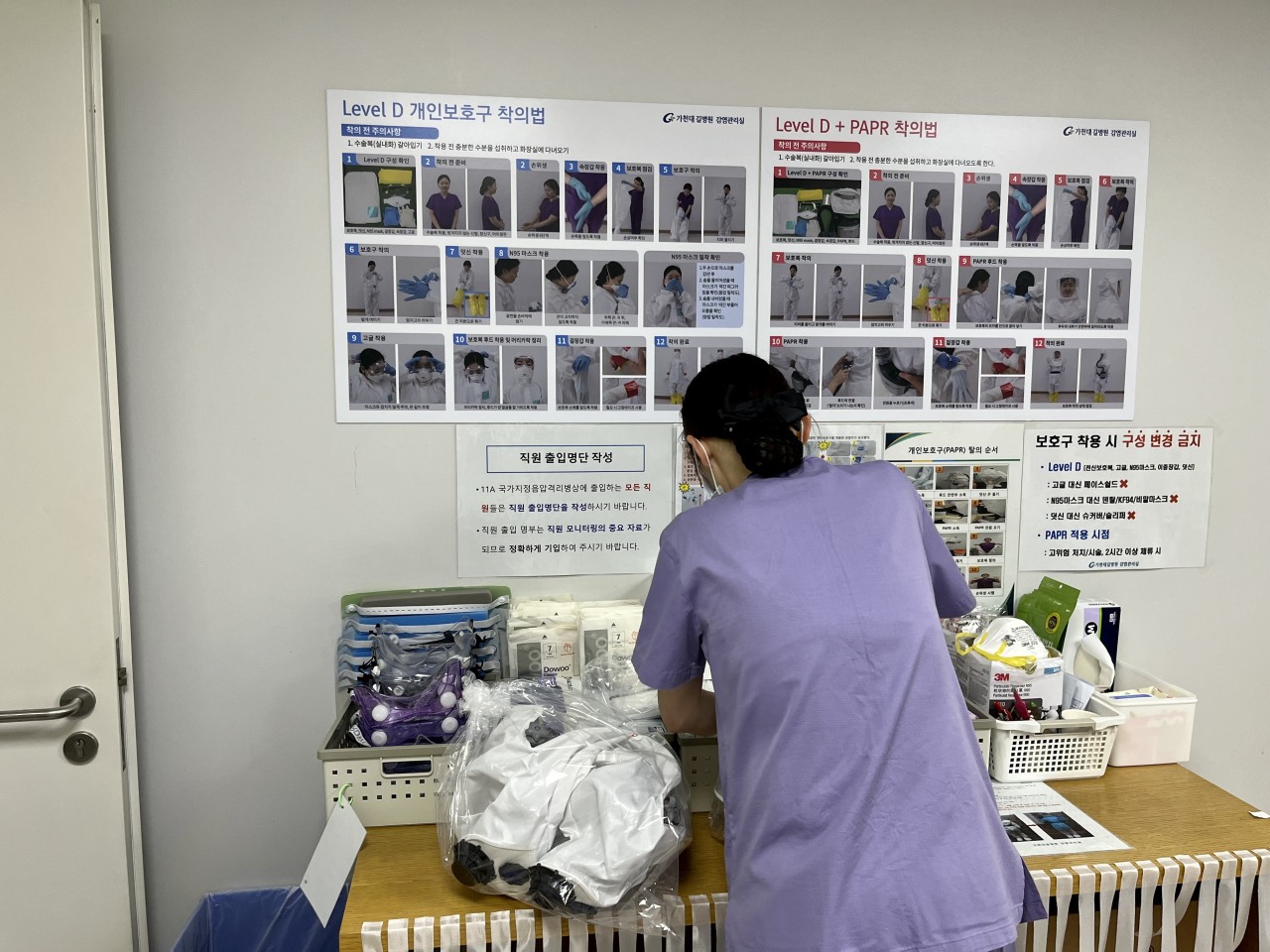 A poster on the wall in the changing room demonstrates proper steps to put on personal protective equipment. “Although it’s a routine procedure, it’s still important to remind ourselves,” Dr. Eom said. (Kim Arin/The Korea Herald)