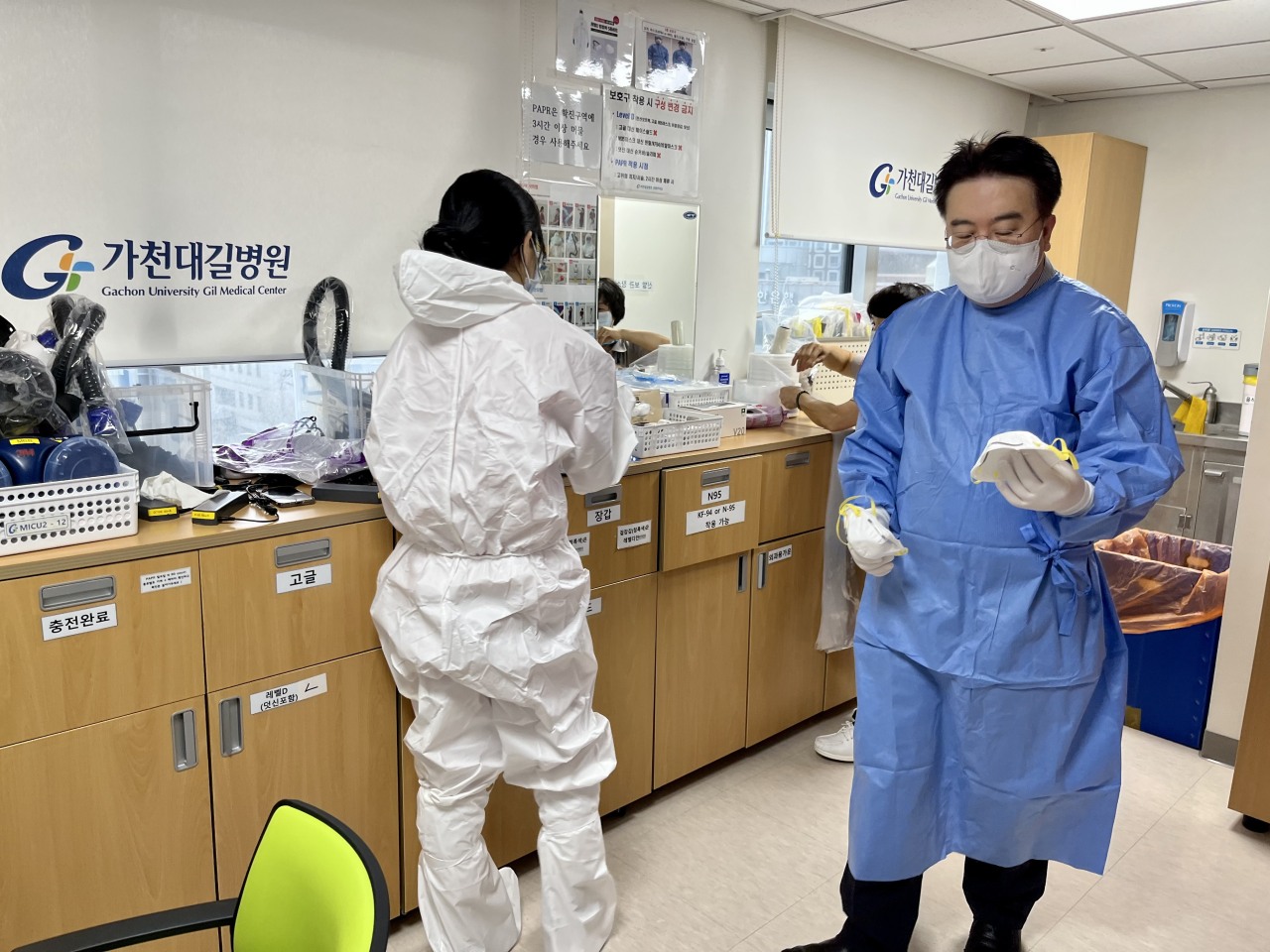 Nurses change into protective suits ahead of their evening shift on Christmas Eve. Dr. Eom, on the right, is seen holding an N95 respirator. (Kim Arin/The Korea Herald)