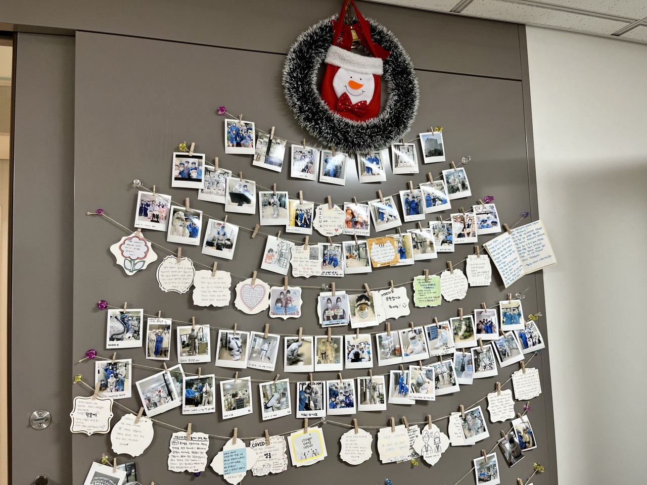 On one the walls of the changing room, polaroid photographs and cards are hung in the shape of a Christmas tree. “So proud of our nursing team looking after severe COVID-19 patients. Thank you all for everything,” read one of the messages. Another read, “Go coronavirus ICU team. We can do this.” (Kim Arin/The Korea Herald)