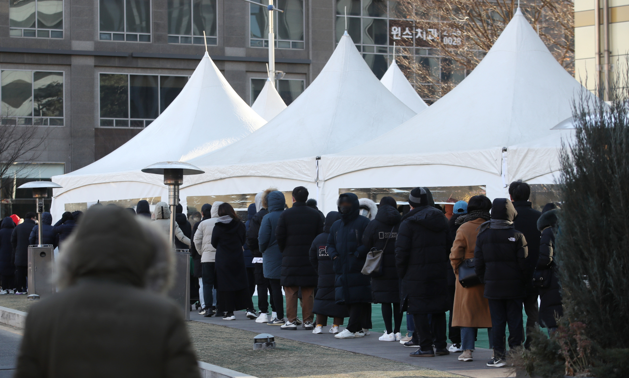 People wait in line to get COVID-19 tests at a makeshift virus testing clinic in Seoul on Sunday. (Yonhap)