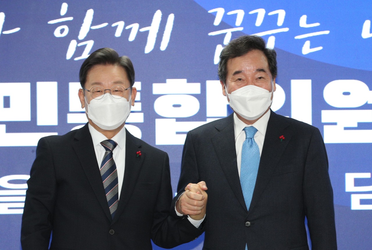 Lee Jae-myung (left), presidential nominee of the ruling Democratic Party of Korea, holds hands with former party chairman Lee Nak-yon (right) in announcing the opening of a sub-committee under the Democratic Party’s presidential election campaign committee at an event held Monday. (Joint Press Corps)