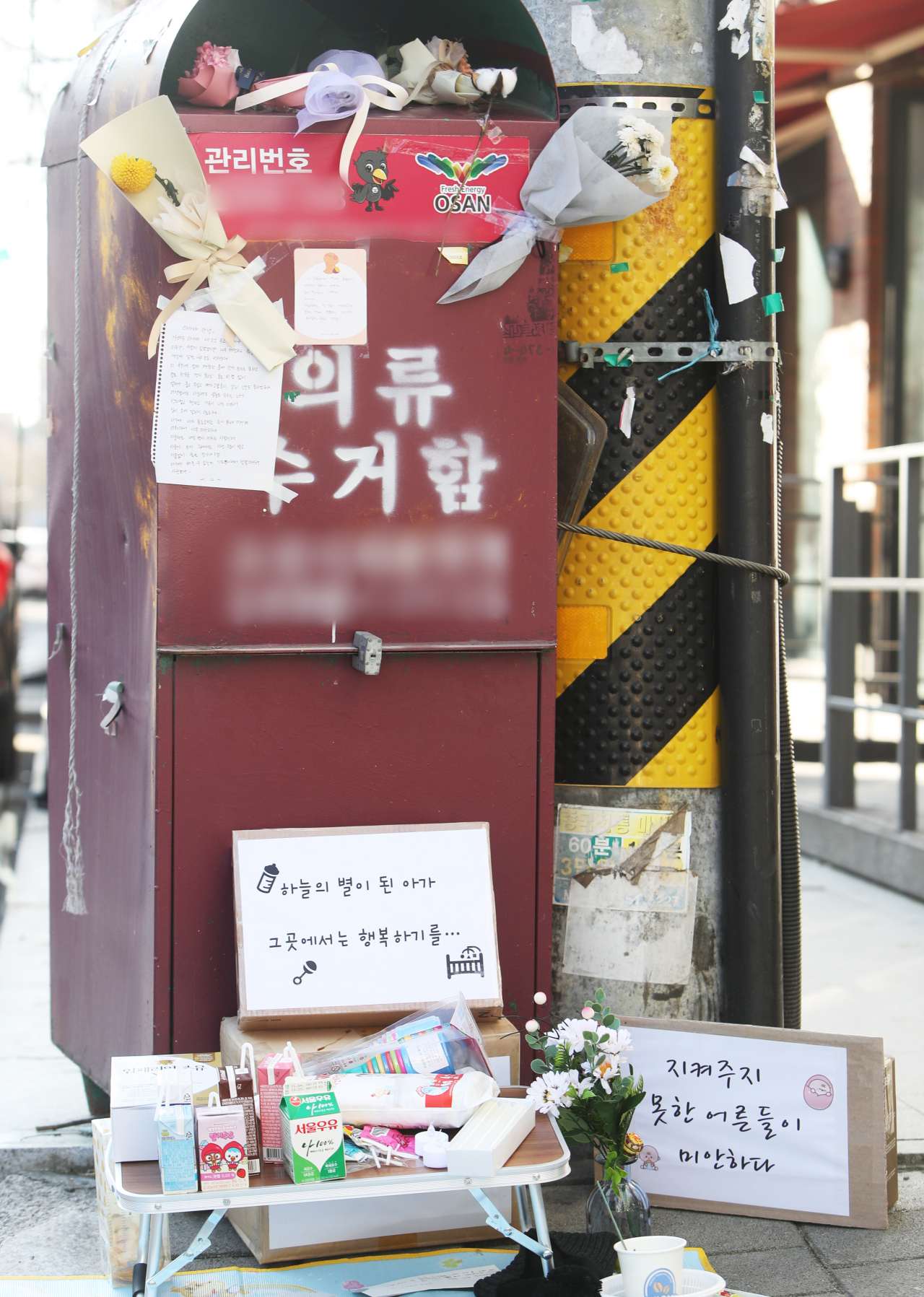 Flowers, letters and gifts are seen at a clothing donation box, inside which a baby was found dead on Dec. 18, in Osan, Gyeonggi Province. (Yonhap)