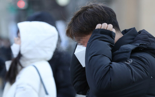 A man covers his ears as he waits to cross the street in Seoul on Monday. (Yonhap)