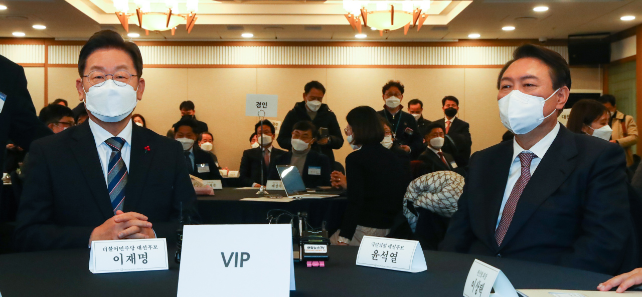 Lee Jae-myung, presidential nominee of the ruling Democratic Party of Korea, is seated at an award ceremony Monday next to his rival Yoon Suk-yeol, presidential nominee of the main opposition People Power Party. (Joint Press Corps)