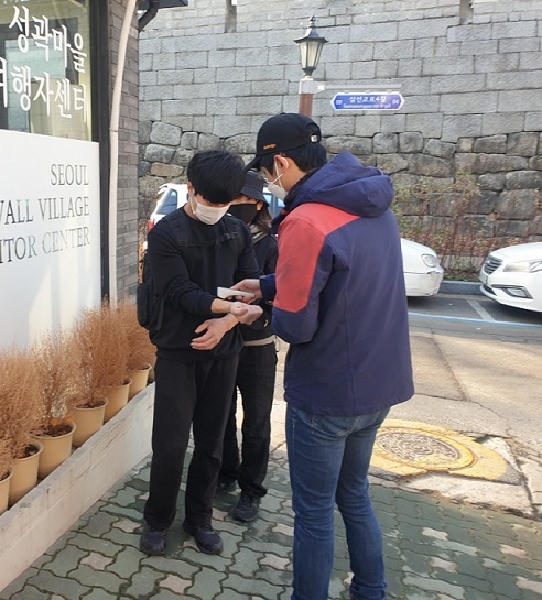 Cho Min-gon (right) of the Coal Briquettes for Neighbors in Korea checks the body temperature of a volunteer. (Choi Jae-hee / The Korea Herald)