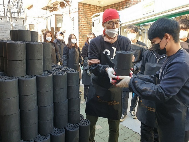 Volunteers receive coal briquettes to deliver. (Choi Jae-hee / The Korea Herald)