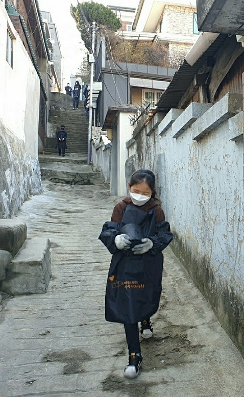 Hong Ah-in, 9, delivers a coal briquette in a narrow alley. (Choi Jae-hee / The Korea Herald)