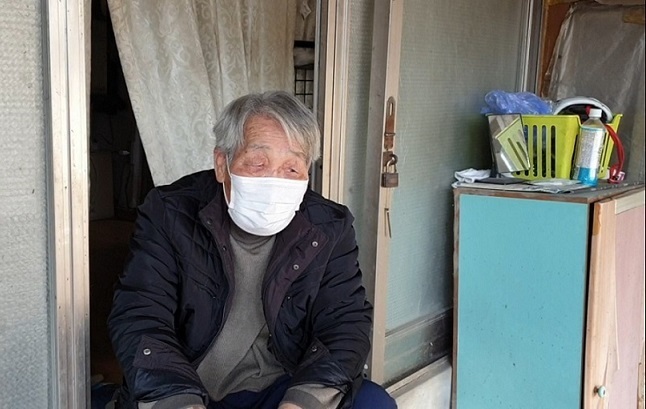 Lee Geun-bok, 84, speaks while watching the volunteers delivering coal briquettes to his house. (Choi Jae-hee / The Korea Herald)