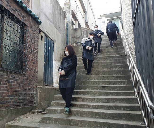 Volunteers walk down stairs carrying coal briquettes. (Choi Jae-hee / The Korea Herald)