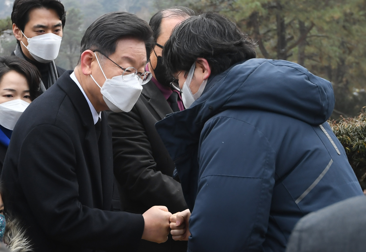 Lee Jae-myung (left), the presidential candidate of the ruling Democratic Party of Korea, greets the son of Kim Geun-tae, a late pro-democracy activist, at Kim’s 10-year commemorative ceremony, held at Moran Memorial Park in Namyangju, Gyeonggi Province, Wednesday. (Yonhap)