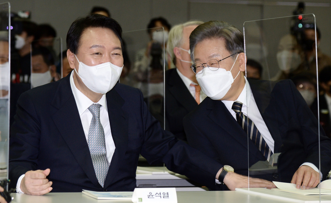 Lee Jae-myung (R), the presidential nominee of the ruling Democratic Party, shares a laugh with Yoon Suk-yeol, the nominee of the main opposition People Power Party, at an event in Seoul marking the 21st anniversary of former President Kim Dae-jung's winning of the Nobel Peace Prize, in the Dec. 9, 2021, file photo. (Yonhap)