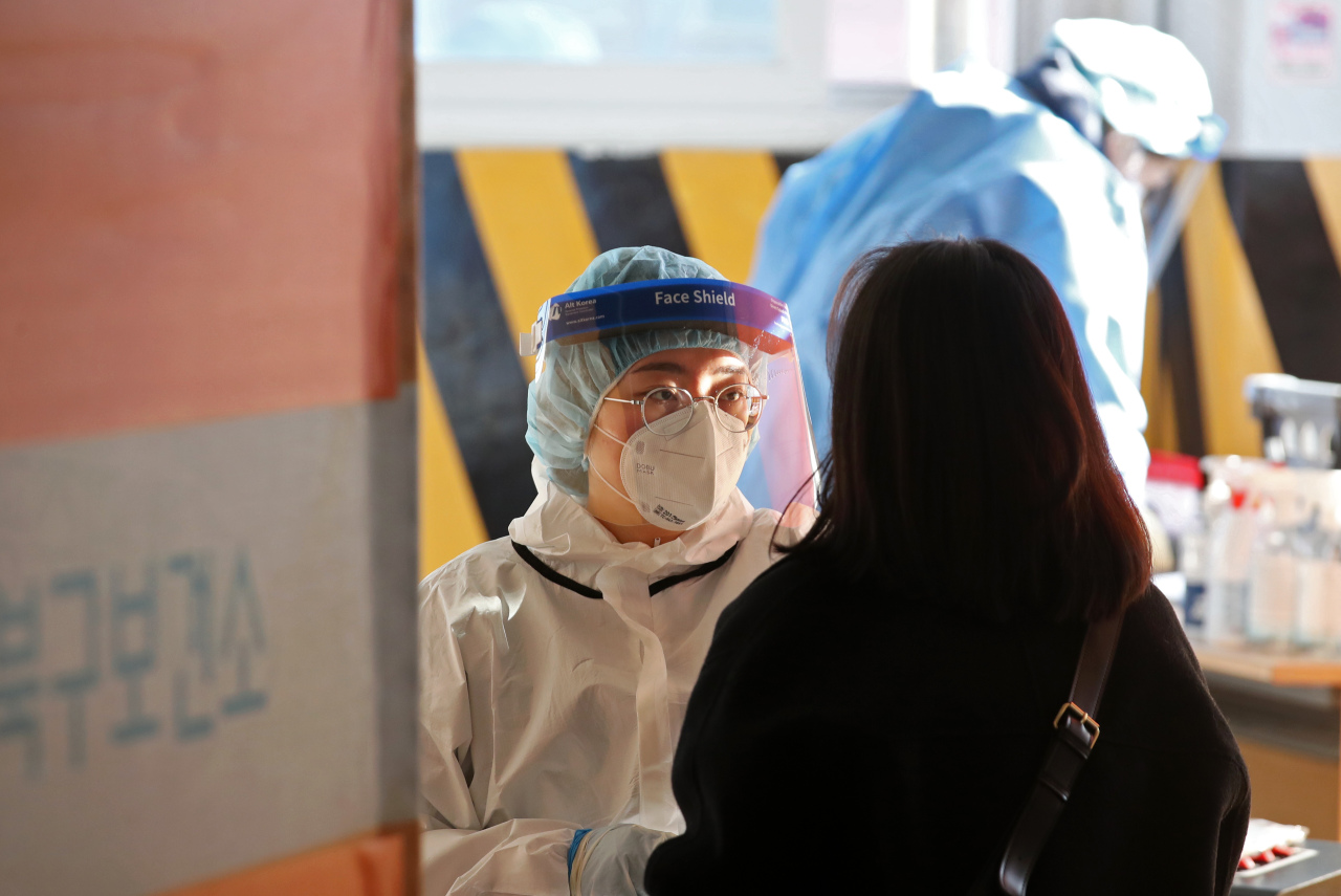 A healthcare worker wearing protective gear takes a sample from a patient at a local COVID-19 testing center. (Yonhap)