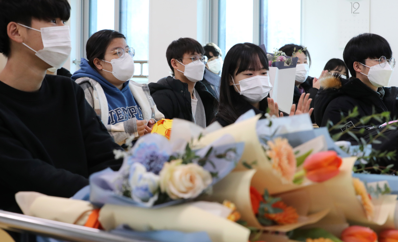 Students wearing masks watch a video at a graduation ceremony held at Haemil Middle School in Sejong on Dec. 31. (Yonhap)