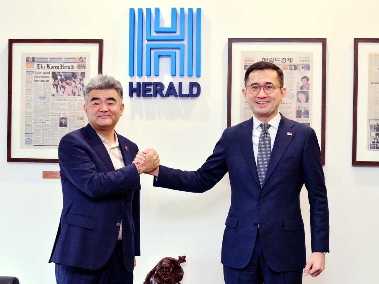 Eric Teo (right), the Singaporean ambassador to Korea, shakes hands with Herald Corp. Chairman Jung Won-ju during a courtesy visit to the Herald Corp. headquarters in central Seoul on Monday.(Park Hyun-koo/The Korea Herald)