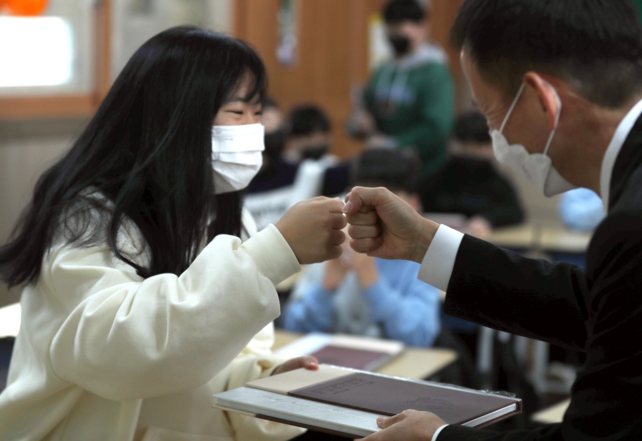 Student receives a fist bump from a principal at a graduation ceremony held at a school in Changwon, South Gyeongsang Province, Thursday. (Yonhap)