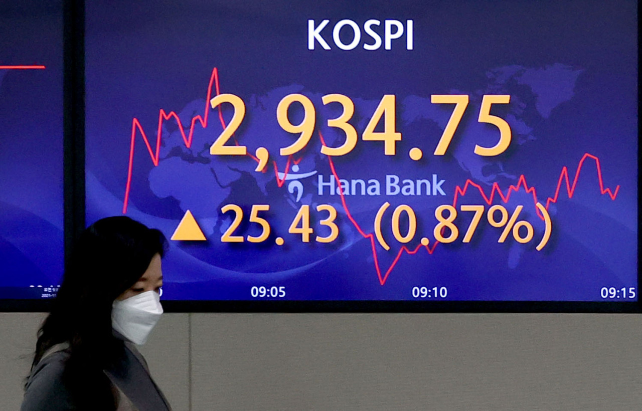 A currency dealer walks past an electronic board showing the Korea Composite Stock Price Index (KOSPI) at a dealing room of the Hana Bank headquarters in Seoul on Tuesday. (Yonhap)