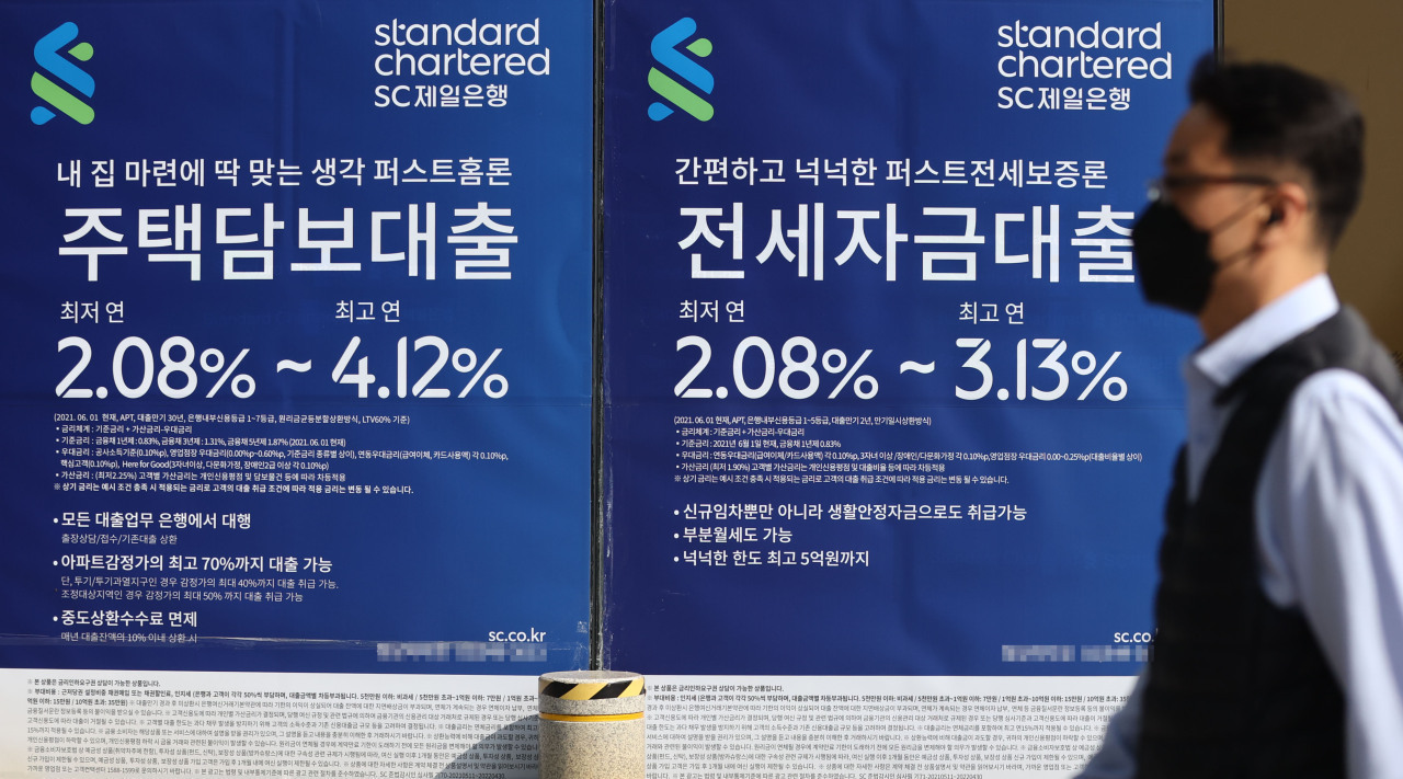 A man passes by advertisements in Seoul promoting Standard Chartered Korea's mortgage products. (Yonhap)