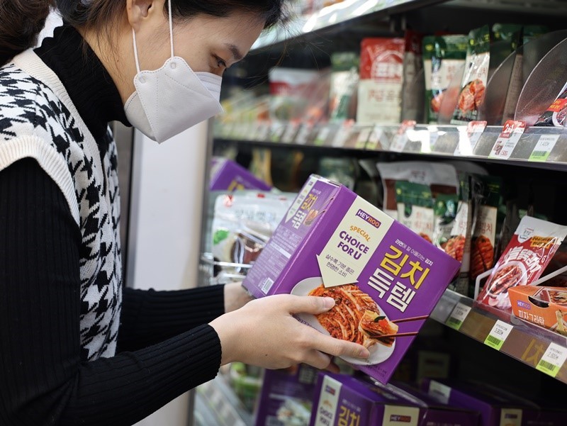A consumer holds a pack of kimchi in a convenience store. (Yonhap)