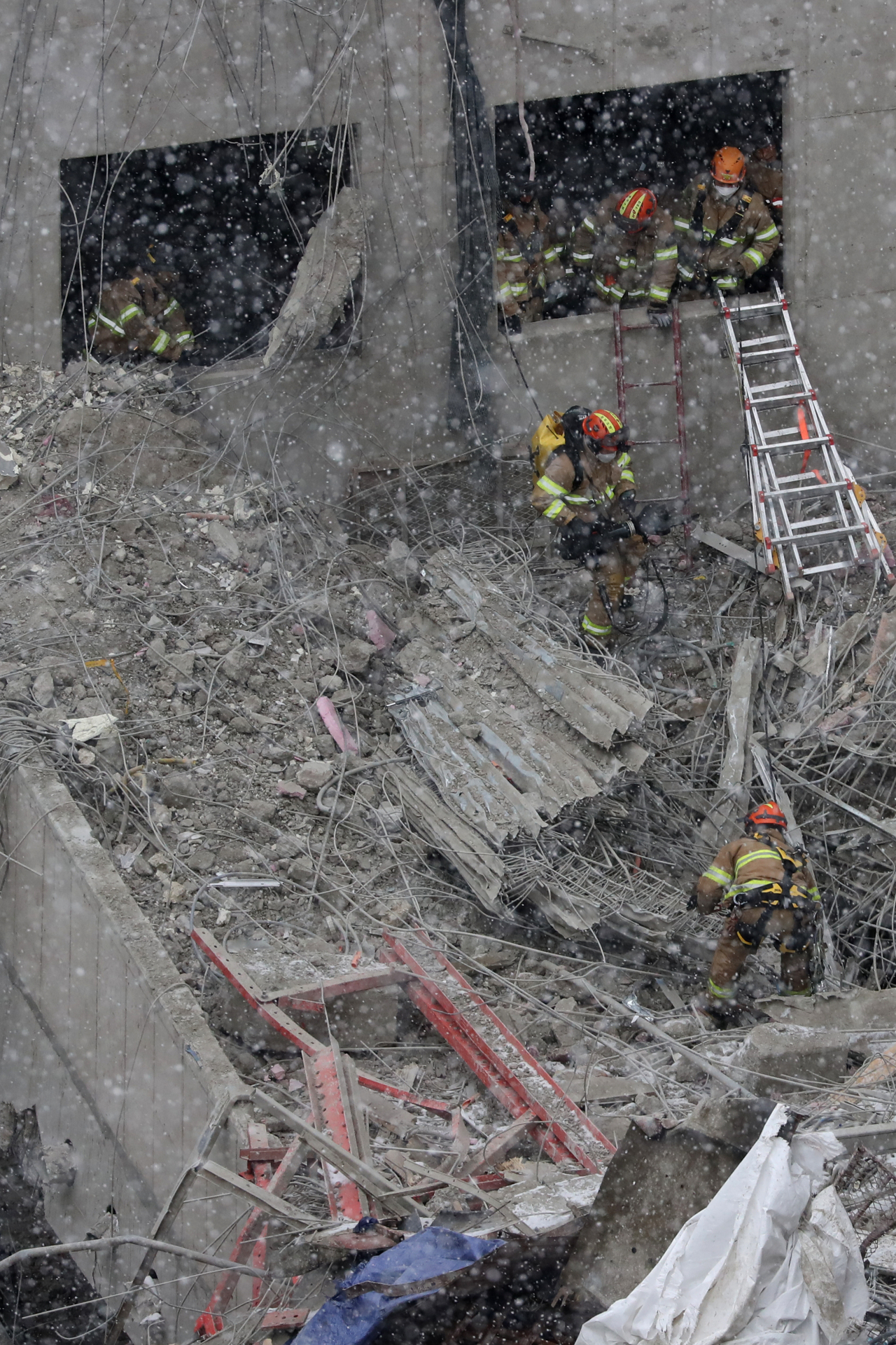 Rescuers comb through debris last Thursday, looking for workers who went missing in a deadly apartment construction accident in the southern city of Gwangju. (Yonhap)