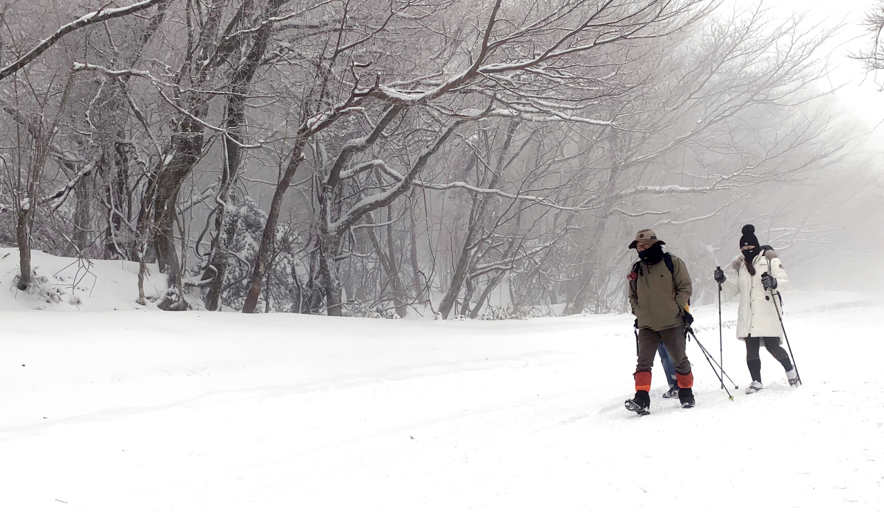 Hikers are seen walking on snow-covered Eorimok Trail on Hallasan, Jeju Island. (Yonhap)