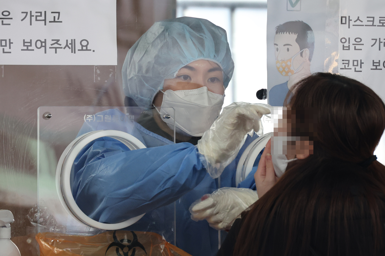 Health official takes a nasopharyngeal swab from a test seeker at a clinic set up outside Seoul Station on Friday.(Yonhap)