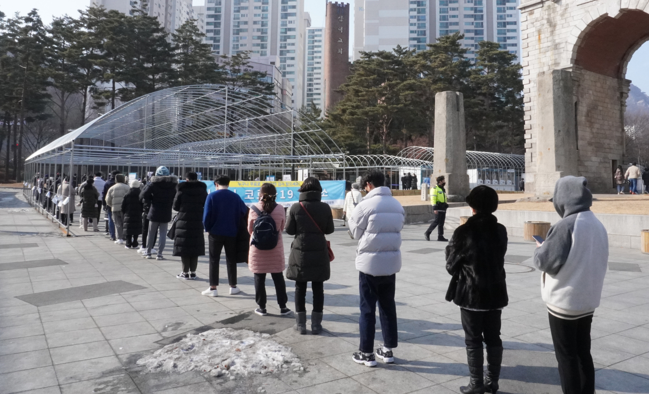 People wait in line to take COVID-19 tests in Seoul on Sunday, as South Korea's daily coronavirus cases spiked to the second-largest figure since the pandemic outbreak amid the fast spread of the omicron variant. (Yonhap)