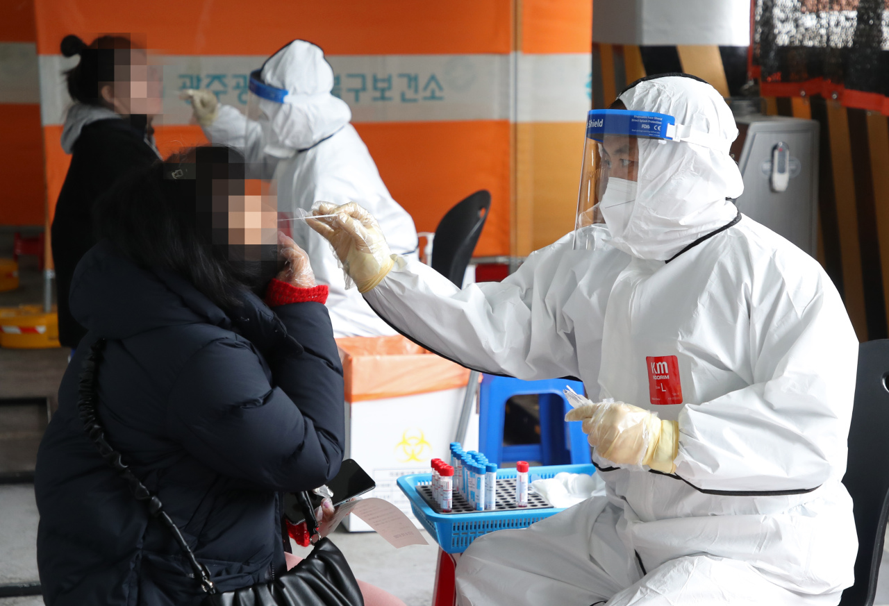 Healthcare workers take samples from visitors to a COVID-19 testing center in Gwangju, Tuesday. (Yonhap)