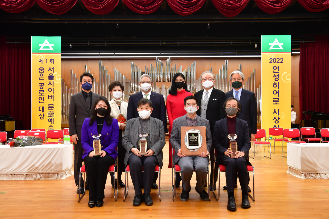 Recipients and judges of the 2022 Unsung Hero Award pose for photos during a ceremony held at the Seoul Cyber University on Monday. (Shinil Educational Foundation)