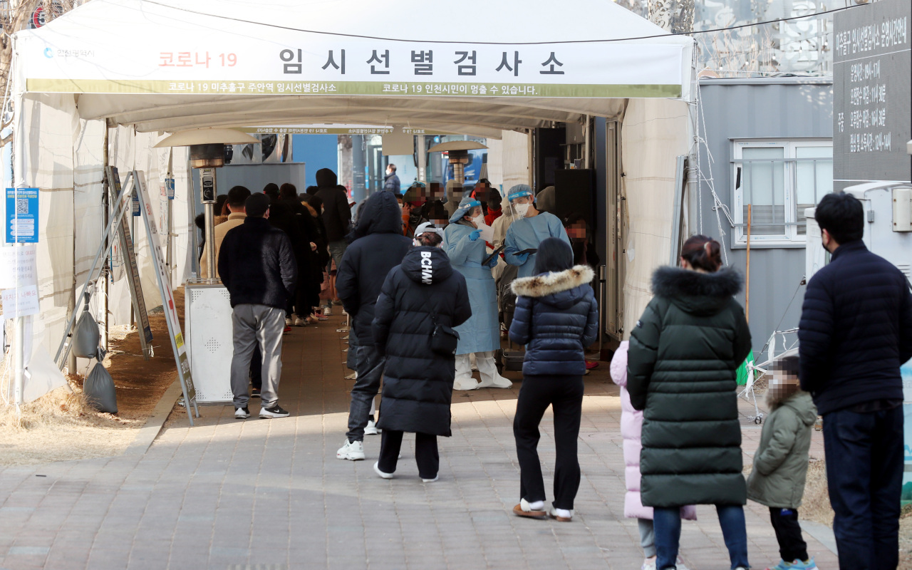 A long line of people waiting to take COVID-19 tests is formed at a temporary testing booth in front of a subway station in Incheon, 40 kilometers west of Seoul, on Thursday. (Yonhap)