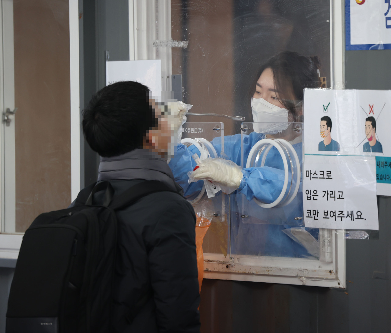 A medical worker carries out a COVID-19 test on a man at a makeshift testing station at Seoul Station in Seoul on Friday. (Yonhap)