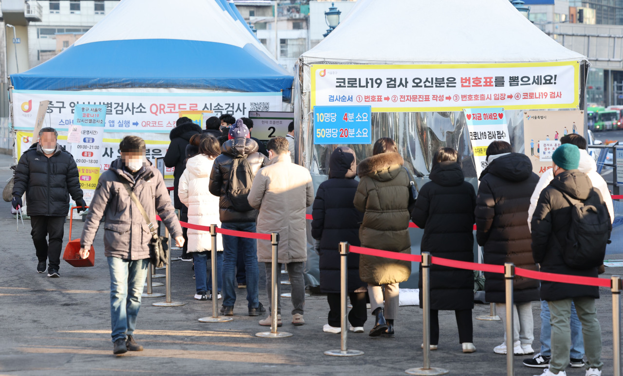 People wait in line for coronavirus tests at a pop-up screening clinic in front of Seoul Station on Friday. (Yonhap)