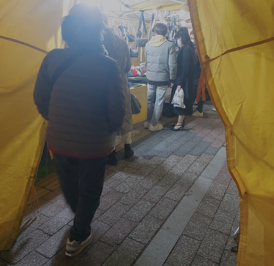 Shoppers at Dongdaemun Saebit Market look at counterfeit luxury items on Wednesday night. (Jie Ye-eun/The Korea Herald)